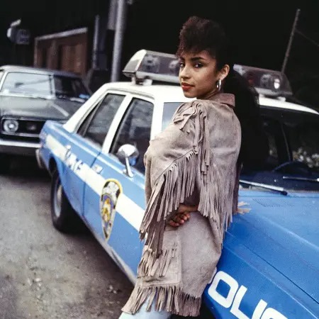 Sade Adu posing in front of a car.